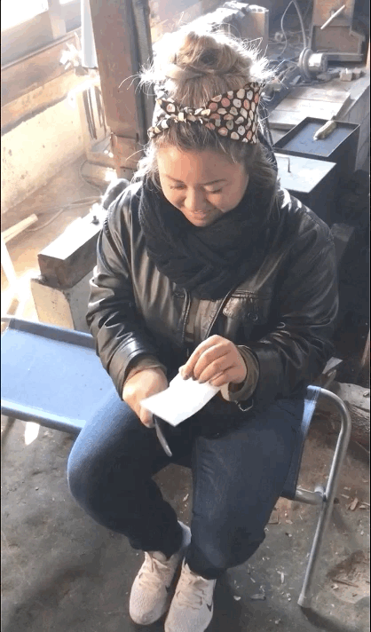 GIF of girl in leather jacket and retrobilly hairstyle cutting a piece of paper with a sharp knife in a Japanese workshop.